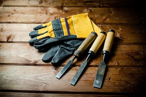 Chisel with construction gloves on the table. Stock Photos