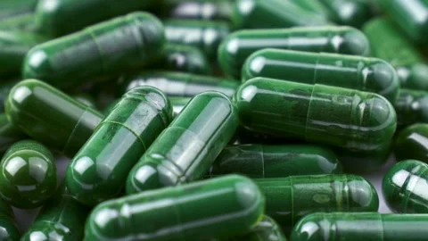Chlorella or spirulina algae green powder capsules circle rotation close up Stock Footage 303891740