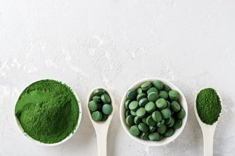 Chlorella or spirulina in the form of tablets and powder on a gray concrete Foto stock