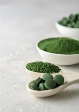 Chlorella or spirulina in the form of tablets and powder on a gray concrete back Stock Photos