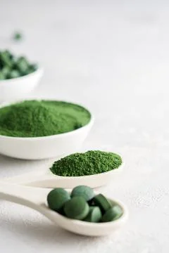 Chlorella or spirulina in the form of tablets and powder on a gray concrete back Stock Photos