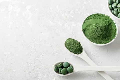 Chlorella or spirulina in the form of tablets and powder on a gray concrete back Stock Photos