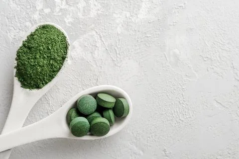 Chlorella or spirulina in the form of tablets and powder on a gray concrete b Foto stock