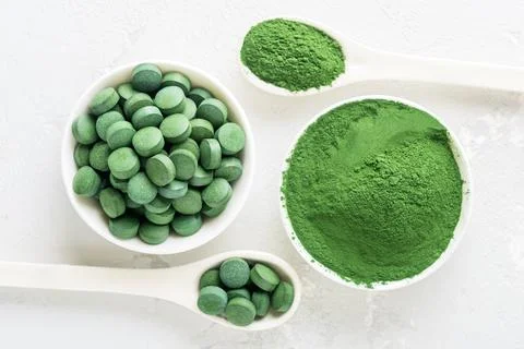 Chlorella or spirulina in the form of tablets and powder on a gray concrete b Stock-Fotos