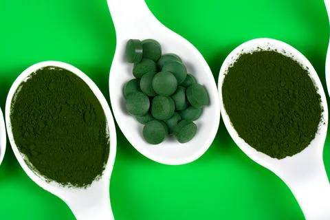 Chlorella or spirulina in the form of tablets and powder on a green backgroun 스톡 사진