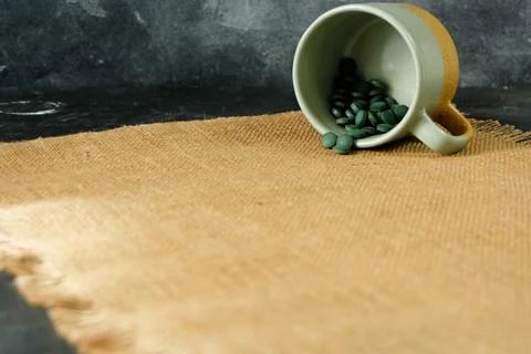 Chlorella or spirulina tablets falling out of mug Stock Photos
