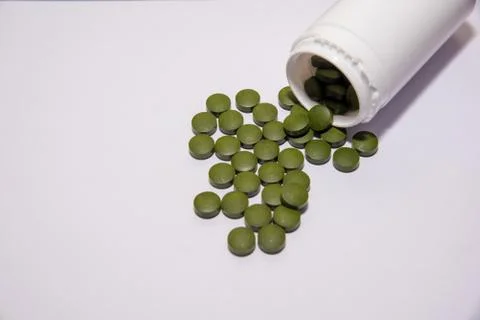 Chlorella tablets and white container on table. Selective focus Stock Photos