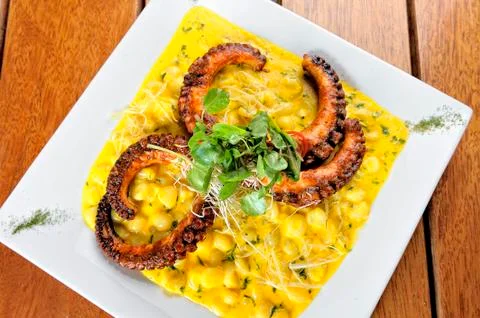 Choclo risotto, with a grilled octopus. On a white background. Stock Photos