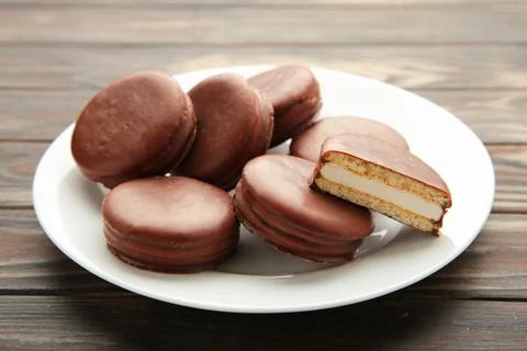 Choco pie chocolate coated snacks in plate on brown wooden background. Stock Photos
