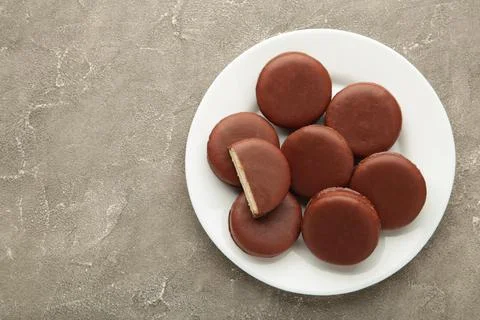 Choco pie chocolate coated snacks in plate on grey background. Stock Photos