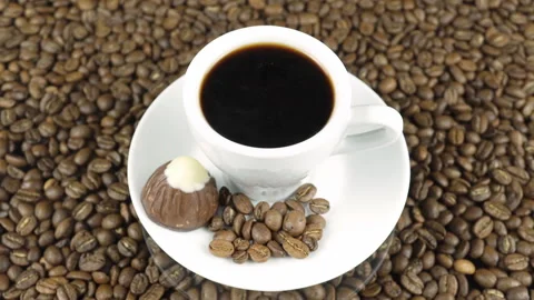 Chocolate And Black Coffee On A Background Of Rotating Coffee Beans. Video stock 196086232