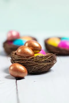 Chocolate and colourful Easter eggs in small nests Stock Photos