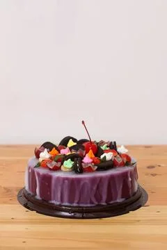 Chocolate and fruit cake with cherry on top on wooden table Stock Photos