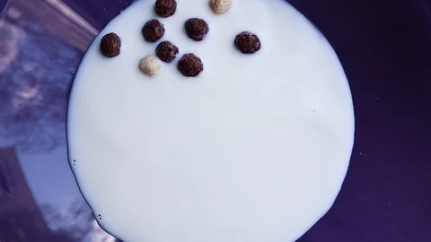 Chocolate and light breakfast cereal are poured into a blue plate with milk Stock Footage 127529902