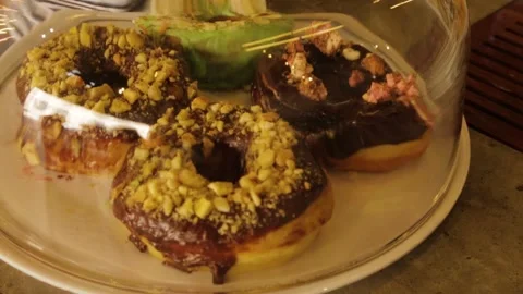 Chocolate and Nut Donuts Under Glass on Cafe Counter in Sydney, Australia Stock Footage 345692107