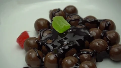 Chocolate balls are pouring by melted cocoa. Candied fruit falls Stock Footage 86996464