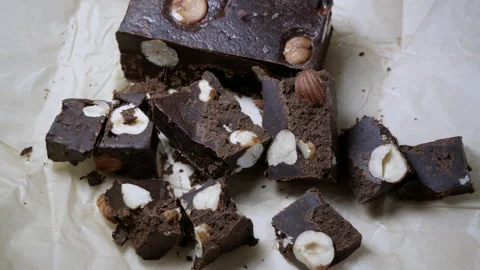 Chocolate bar cut into chunks with whole hazel nuts tasty dessert close up Stock Footage 130883235