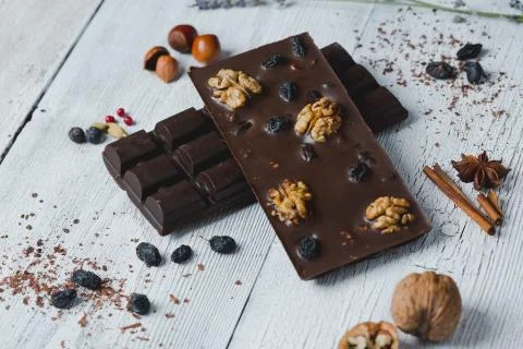 Chocolate bar filled with different berries and nuts  lie old wooden table wi Stock Photos