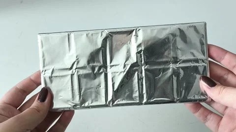 Chocolate bar in foil in hands on a white background. Sweets. Dark chocolate 库存影片 330156701