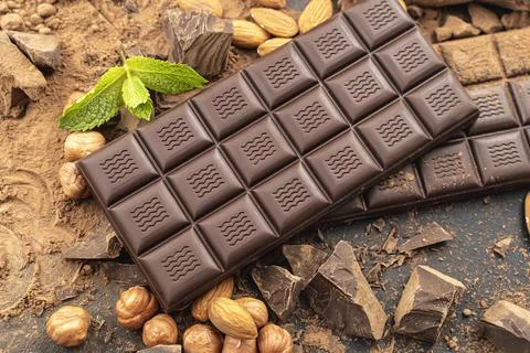 Chocolate bar with hazelnuts, mint leaf, handmade sweets. Composition of bars Foto stock