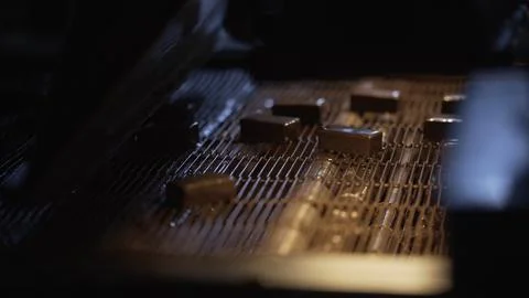 Chocolate bars cooling down on conveyor belt in factory. Stock Photos