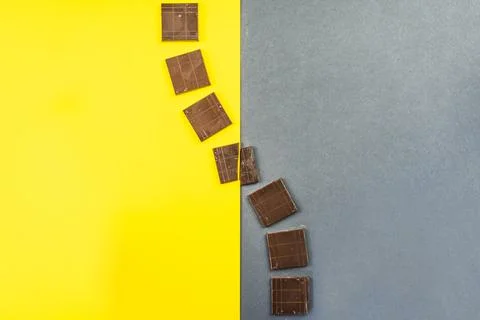 Chocolate bars create geometric shapes on a yellow and gray background Stock Photos