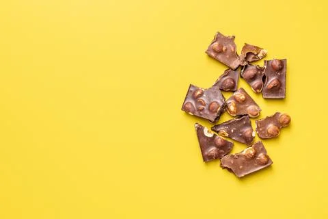Chocolate bars with nuts on yellow background. Stock Photos