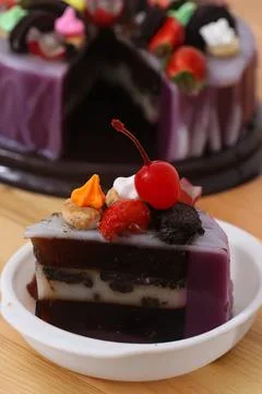 Chocolate berry cake slice with cherry on top on a white dish Stock Photos