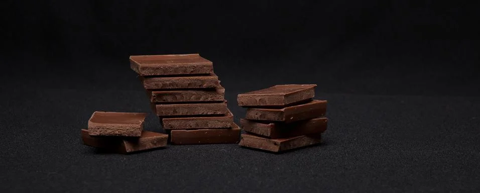 Chocolate blocks stack on black background, copyspace for your text Stock Photos