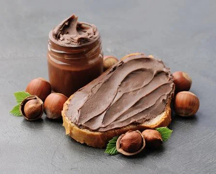 Chocolate breakfast. Bread with chocolate paste with filbert nuts closeup. Stock Photos