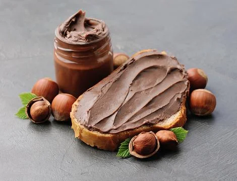 Chocolate breakfast. Bread with chocolate paste with filbert nuts closeup. Foto stock
