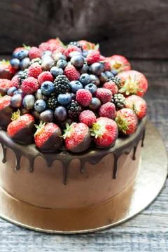 Chocolate brownie cake with fresh summer berries. Decorated with strawberries Stock Photos