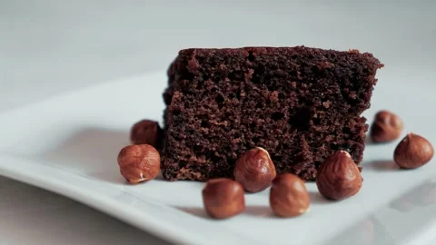 Chocolate brownie filled with hazelnuts in a white plate Stock Footage