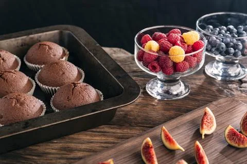Chocolate cake in baking pan and fresh seasonal berries on wooden table. Home Stock Photos