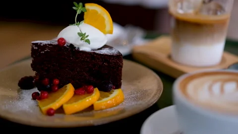 Chocolate cake close-up with whipped cream and orange slices in a cozy café 스톡 동영상 341684654