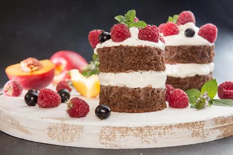 Chocolate cake decorated with raspberry, black currant, nectarine, wipped cre Stock Photos