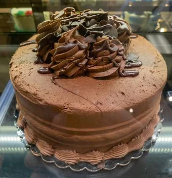 Chocolate cake on display in a display case at a grocery store Stock Photos