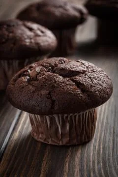 Chocolate cake muffins on a table. Dark lighting Stock Photos