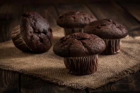 Chocolate cake muffins on a table. Dark lighting Stock Photos