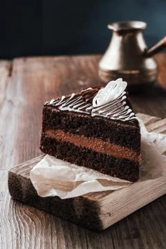 Chocolate cake side view on a cutting board rustic on a wooden table. Stock Photos