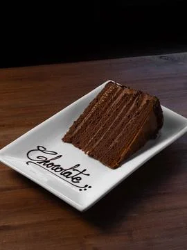 Chocolate cake slice rests on white plate Stock Photos
