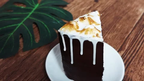 Chocolate cake slice with toasted meringue and glossy white glaze dripping down Stock Footage 333118052