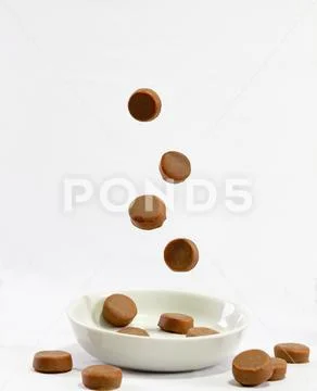 Chocolate candies falling onto the plate Stock Photos