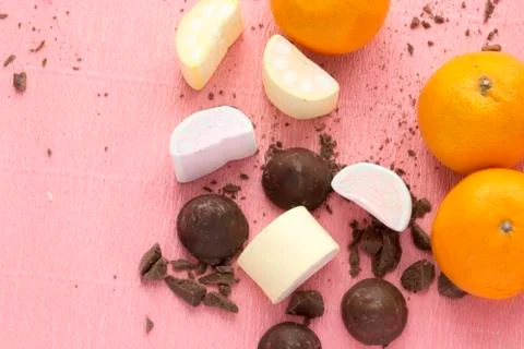 Chocolate candies with orange and marshmallows. Sweets, citrus, desserts on pink Stock Photos