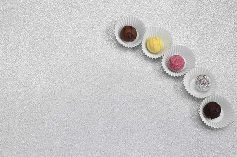 Chocolate candy assortment arranged in diagonal row on light textured background Stock Photos