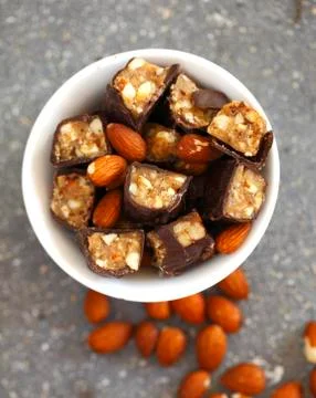 Chocolate candy bars cut into pieces mixed with whole almonds in white porcelain Stock Photos