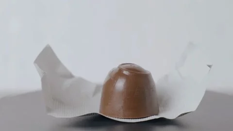 A chocolate candy on a foil wrapper lies on a turntable and spins Stock Footage 230013277