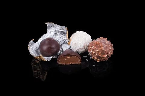 Chocolate candy on reflective black surface different colors and shapes. Hand Stock Photos