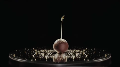 Chocolate candy on the round mirror and a cloud of golden confectionery dust Stock Footage 149147857