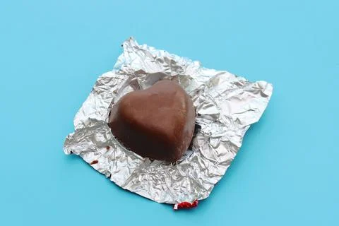 Chocolate candy with wrapper on a blue background. Stock Photos
